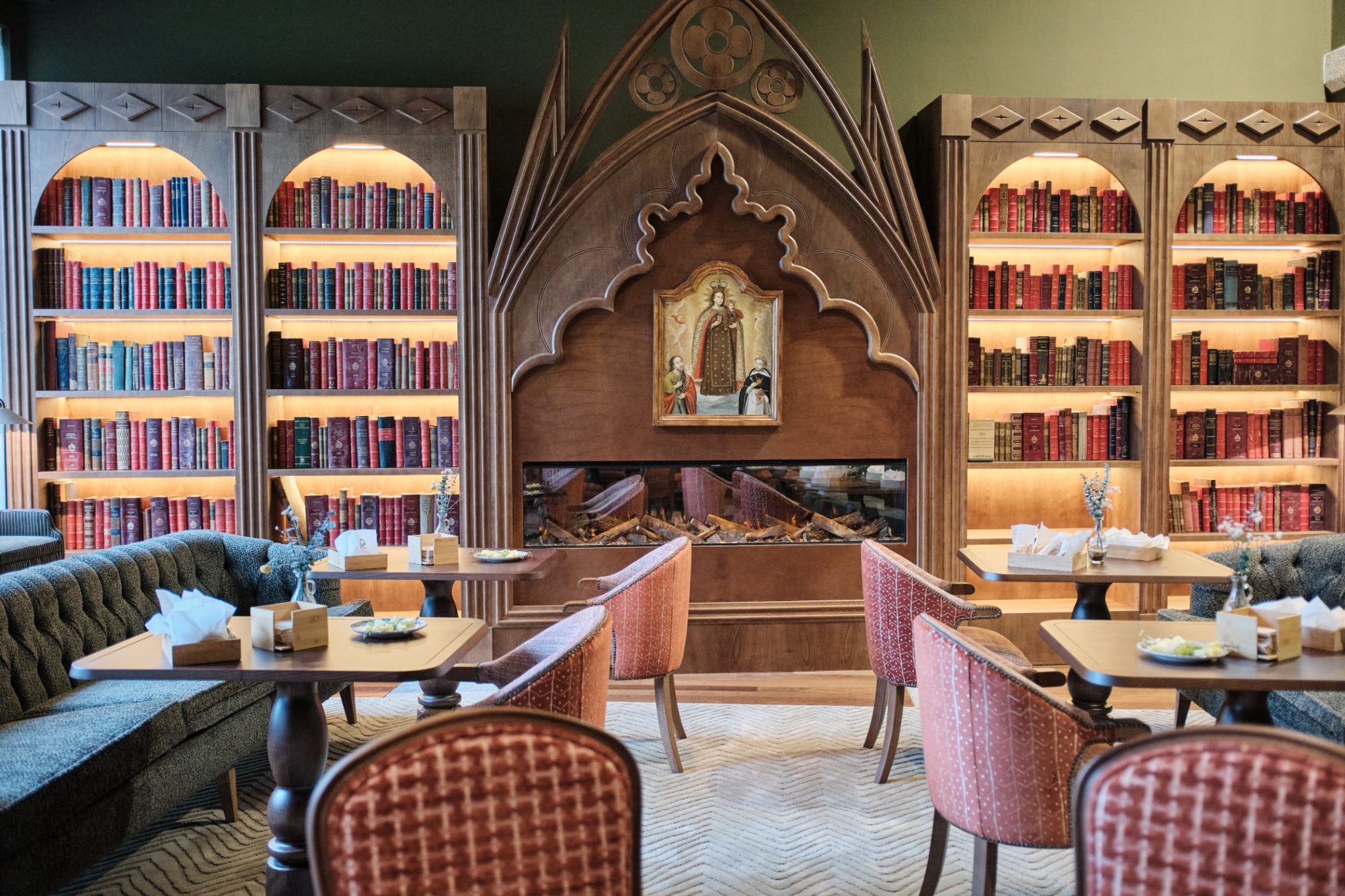 Salón con librerías iluminadas, chimenea y mesas preparadas para recibir a los invitados
