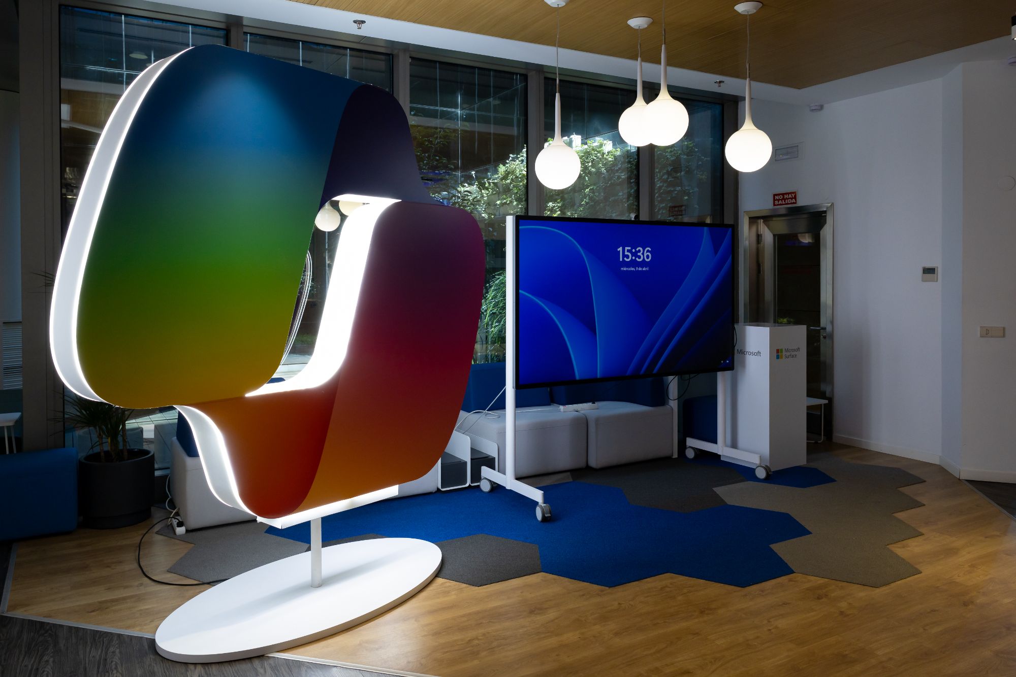 Instalación de marca retroiluminada junto a una pantalla interactiva en un espacio expositivo