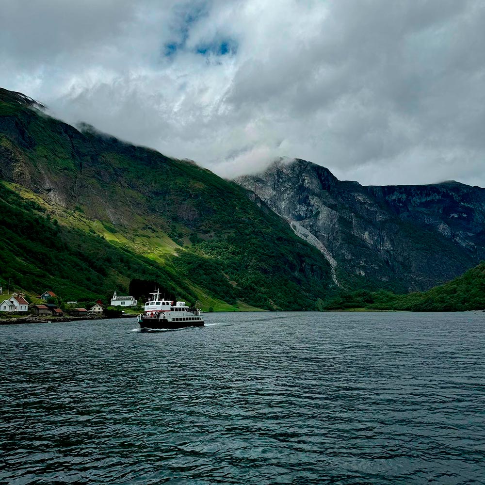Barco navegando por un fiordo bajo las nubes