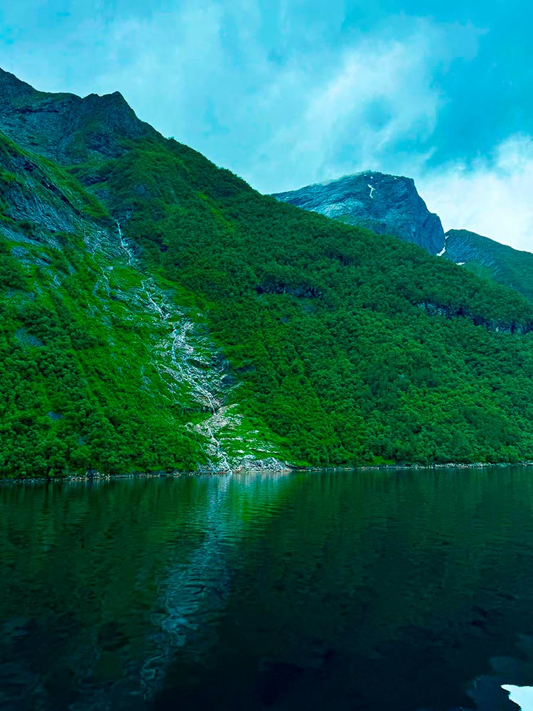 Ladera verde con cascada reflejada en el agua